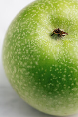 Green granny smith apple with white dots on the peel. Macro, selective focus