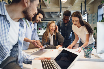 Team of diverse coworkers in modern office discuss their project together