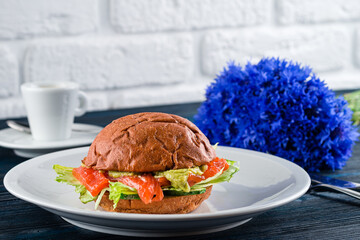 Fish burger with salted salmon and avocado on Black background. Healthy Salmon Burger