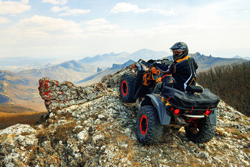 Man in helmet sitting on ATV quad bike in mountains © fotofabrika