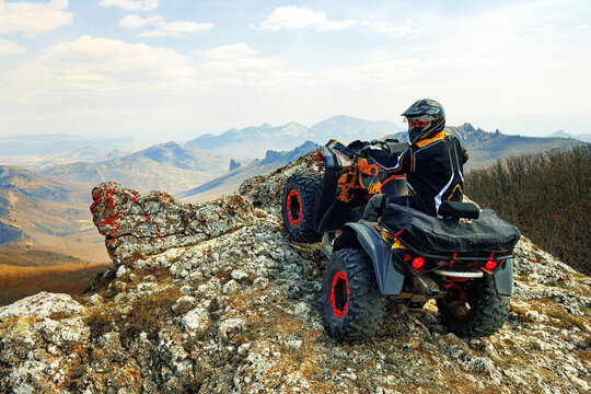 Man in helmet sitting on ATV quad bike in mountains