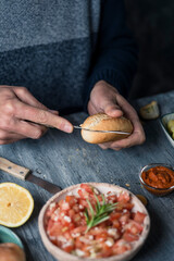 man cutting a bread bun to prepare a sandwich