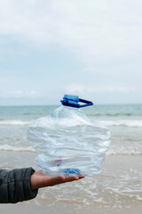 man with a crushed plastic bottle on the beach