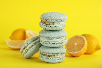 Fototapeta na wymiar Delicious macarons and fresh lemons on yellow background