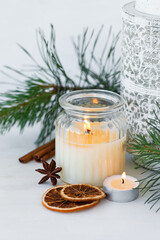 Obraz na płótnie Canvas Rustic zero waste natural christmas decor. Candle in glass jar, spices, dry orange, green fir tree banches. Decoration for holiday dinner table. Happy new year. Holiday atmospere, festive mood