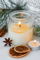 Rustic zero waste natural christmas decor. Candle in glass jar, spices, dry orange, green fir tree banches. Decoration for holiday dinner table. Happy new year. Holiday atmospere, festive mood