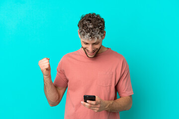 Young handsome caucasian man isolated on blue background surprised and sending a message