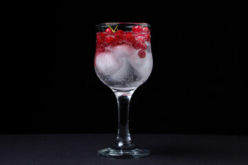 Refreshing cocktail with ice and red currants on a black background. Non-alcoholic cocktail.
