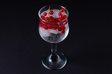 Refreshing cocktail with ice and red currants on a black background. Non-alcoholic cocktail.