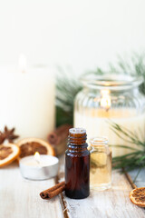 Assortment of natural christmas essential oils in small bottles. Candles, branches of fir tree....