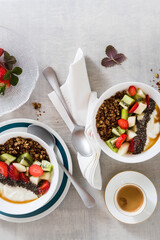 breakfast with granola, yogurt, fresh fruit, chia seeds, maple syrup and berries in plates on the table