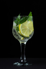 Refreshing cocktail with ice, lemon and mint on a black background. Non-alcoholic cocktail.