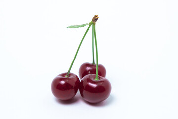 Ripe cherries on a white background. Three cherries on one branch. Delicious fruit
