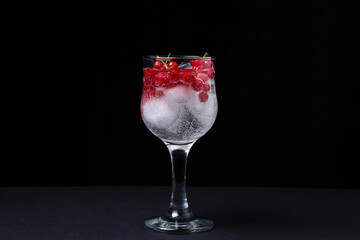 Refreshing cocktail with ice and red currants on a black background. Non-alcoholic cocktail.