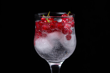 Refreshing cocktail with ice and red currants on a black background. Non-alcoholic cocktail.