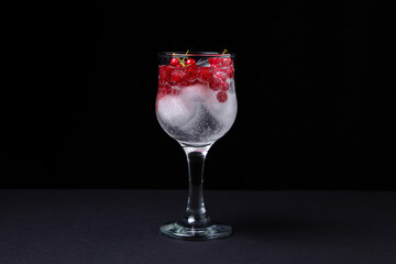 Refreshing cocktail with ice and red currants on a black background. Non-alcoholic cocktail.