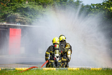 Two firefighter water spray by high pressure nozzle in fire fighting operation. Fire and rescue training school regularly to get ready.