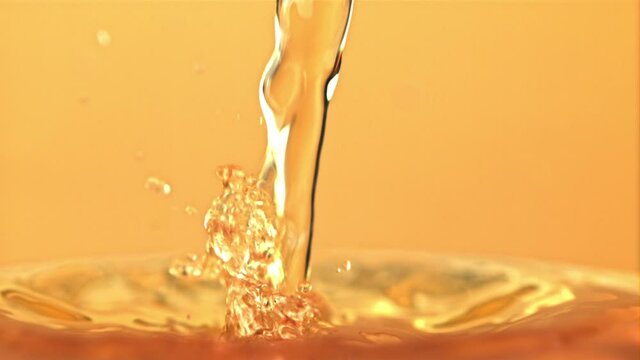 Super slow motion apple juice pours with splashes. On a yellow background. Filmed on a high-speed camera at 1000 fps.