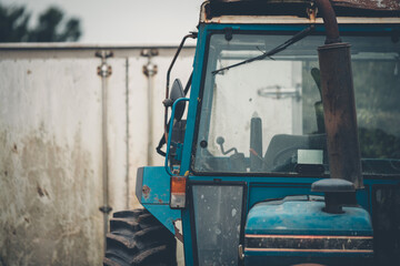 An abandoned old blue tractor stored in a field in the UK with overcast skies