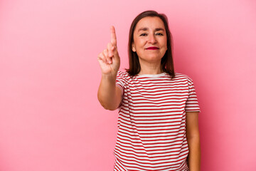 Middle age caucasian woman isolated on pink background showing number one with finger.