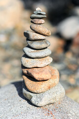 Fototapeta na wymiar Hand building a pile of smooth stones on the beach 
