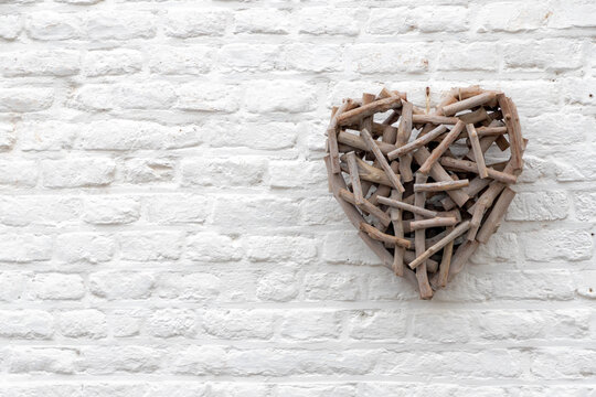 Weaving brown wooden heart on white brick wall, Heart shaped from scantling wood with free copy space, Abstract geometric pattern, Can be used as background for display or montage your products.