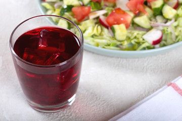 Dinner table with vegetable salad and red wine in a glass