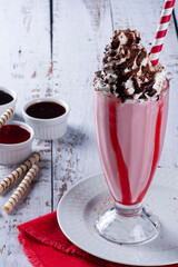 Beautiful glass of strawberry milkshake with whipped cream and chocolate sauce