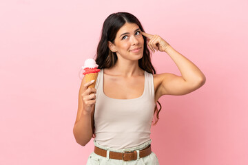 Young caucasian woman with a cornet ice cream isolated on pink background having doubts and thinking