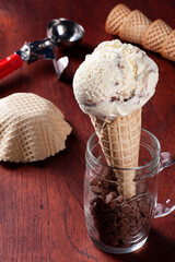 .Vanilla ice cream with chocolate in woth waffle cone on wooden background. Copy space