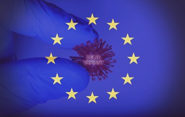Hand of a doctor holding the new Delta Variant virus, with a european flag as a background.