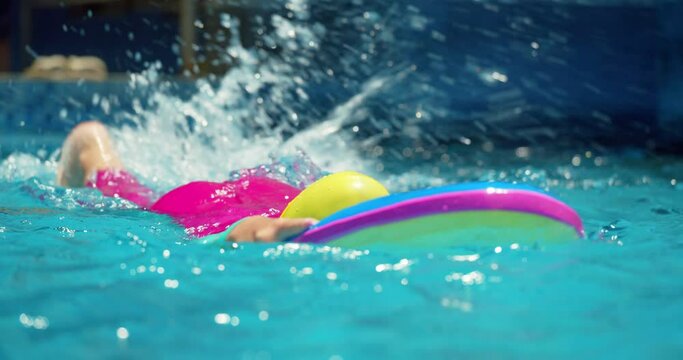 A cute little child in swimming caps performs an assignment in a swimming lesson in the pool.