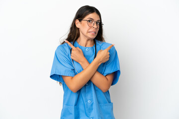 Young surgeon doctor caucasian woman isolated on white background pointing to the laterals having doubts