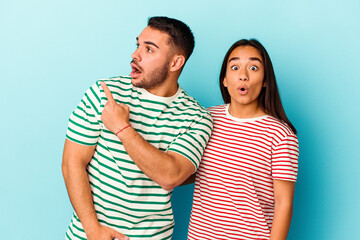 Fototapeta premium Young mixed race couple isolated on blue background pointing to the side