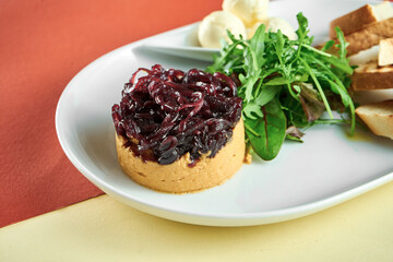 Turkey liver pate with onion confit, curtons in a white plate on bright colored backgrounds