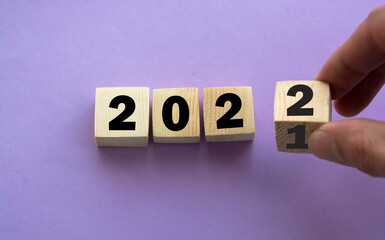 Businessman hand holding wooden cube with flip over block 2021 to 2022 START word on table...