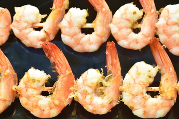 baked shrimp with butter and salt stabbing wooden stick on plate dipping spicy chili sauce