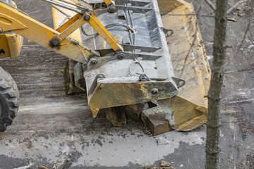 Large heavy duty yellow road work bulldozer refreshes asphalt pavement and curbs