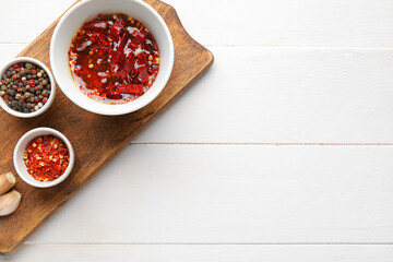Board with hot honey and ingredients on light wooden background