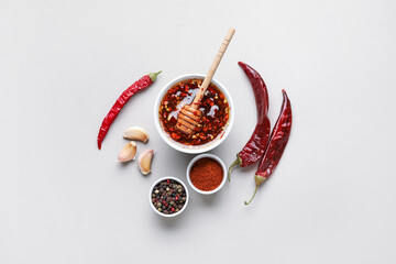 Bowl of hot honey and ingredients on grey background