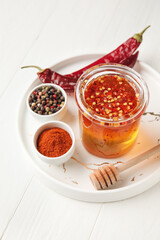Tray with hot honey and ingredients on light wooden background