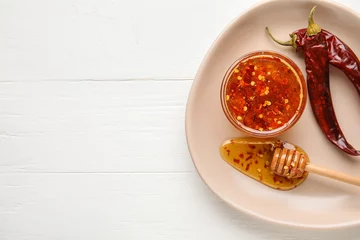 Foto op Canvas Plate with hot honey and chili peppers on light wooden background © Pixel-Shot