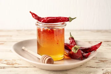 Gordijnen Jar of hot honey and dry chili peppers on light wooden background © Pixel-Shot
