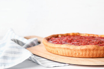 Board with tasty Chicago-style pizza on light background