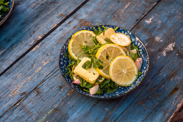 Bowl of a mix of lemon slices and cut parsley on a wooden table - stuffing for fi