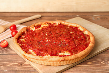 Board with tasty Chicago-style pizza on wooden background