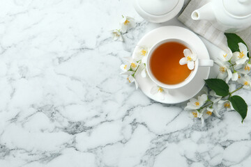 Fototapeta na wymiar Aromatic jasmine tea and fresh flowers on white marble table, flat lay. Space for text