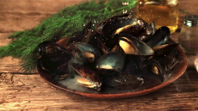 Super slow motion on the mussels in the plate fall water. On a wooden background. Filmed on a high-speed camera at 1000 fps.