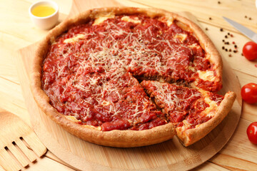 Board with tasty Chicago-style pizza and ingredients on wooden background, closeup