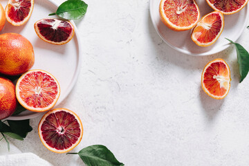 Composition of whole and sliced blood oranges in a plate on white table background. Flat lay, top view, copy space.